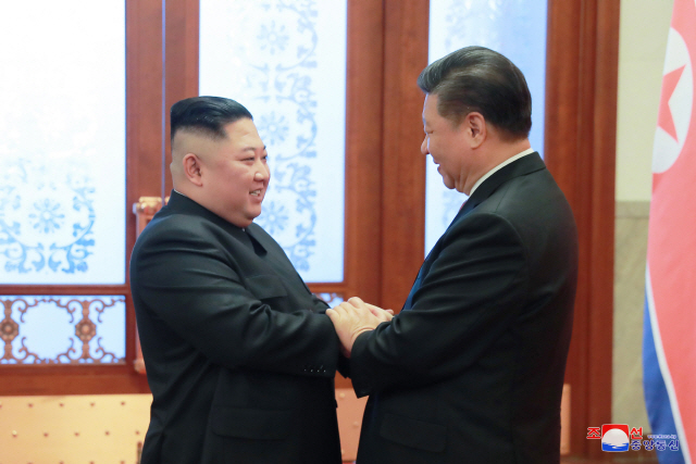 지난 1월 8일 베이징 인민대회당에서 김정은 북한 국무위원장과 시진핑 중국 국가 주석이 손을 잡고 인사하고 있다./연합뉴스