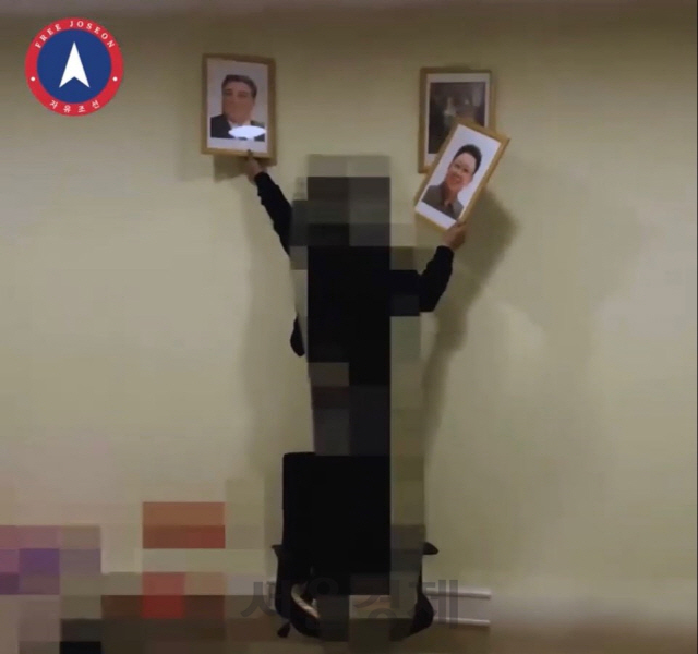 자유조선이 지난 20일 홈페이지에 올린 영상에서 한 남성이 벽에 걸린 김일성·김정일 초상화를 떼어 내고 있다./자유조선 홈페이지 캡쳐