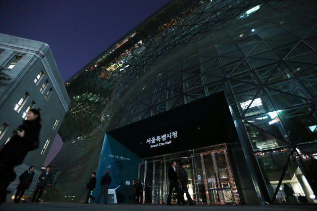 서울시청사 불이 꺼진 가운데 공무원들이 퇴근을 하고 있다.       /연합뉴스