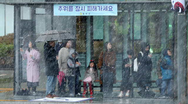 서울 곳곳에 갑작스럽게 눈과 비가 섞인 진눈깨비가 내린 23일 서울 광화문 버스 정류장에서 시민들이 버스를 기다리고 있다. /연합뉴스