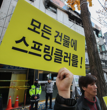 전국세입자협회 회원들이 지난해 11월 화재로 7명의 시민이 숨진 서울 종로구 관수동 고시원 화재 현장 앞에서 모든 건물에 스프링클러 설치를 요구하는 시위를 벌이고 있다. /연합뉴스