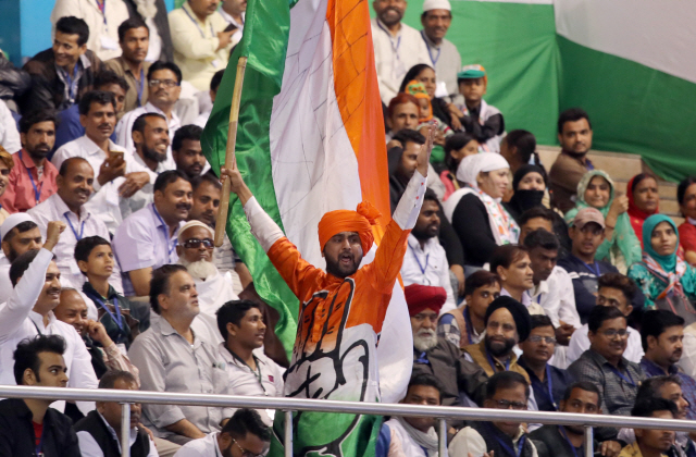 정치 명문 ‘네루·간디’가(家)의 후예인 라훌 간디 인도국민회의(INC) 총재의 지지자 집회 연설을 앞두고 지난 11일(현지시간) 한 남성이 인도 국기를 흔들며 환호하고 있다. /블룸버그