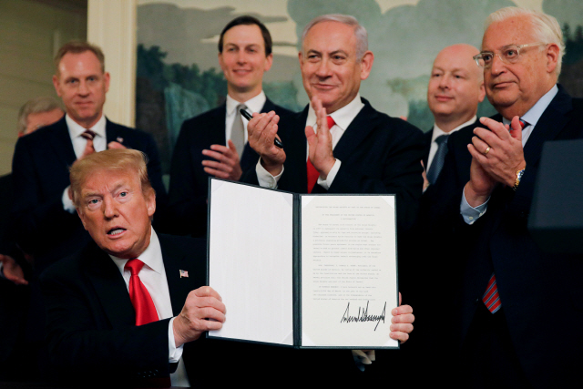 도널드 트럼프(왼쪽) 미국 대통령이 25일(현지시간) 백악관에서 골란고원에 대한 이스라엘의 주권을 인정하는 포고문에 서명한 뒤 이를 들어 보이자 베냐민 네타냐후(뒷줄 가운데) 이스라엘 총리가 활짝 웃으며 박수 치고 있다.   /워싱턴DC=로이터연합뉴스