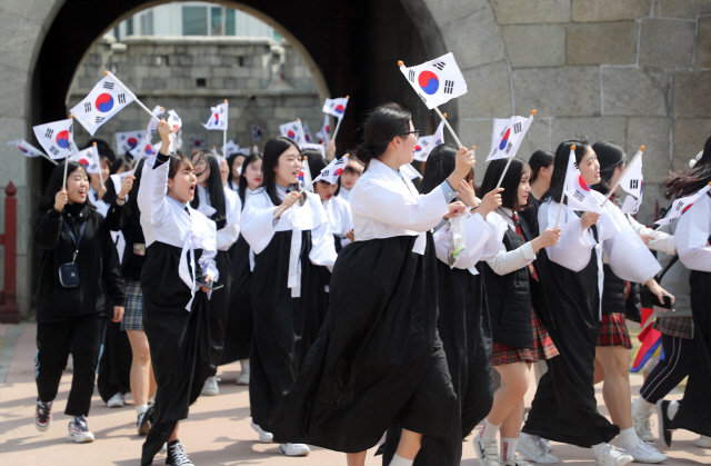 전주지역 중·고교생들이 27일 전북 전주 풍남문에서 3·1운동 100주년을 기념해 열린 ‘독립의 횃불, 전국 릴레이’ 행사에 참석해 당시 모습을 재현한 한복을 입고 태극기를 흔들고 있다. /전주=연합뉴스