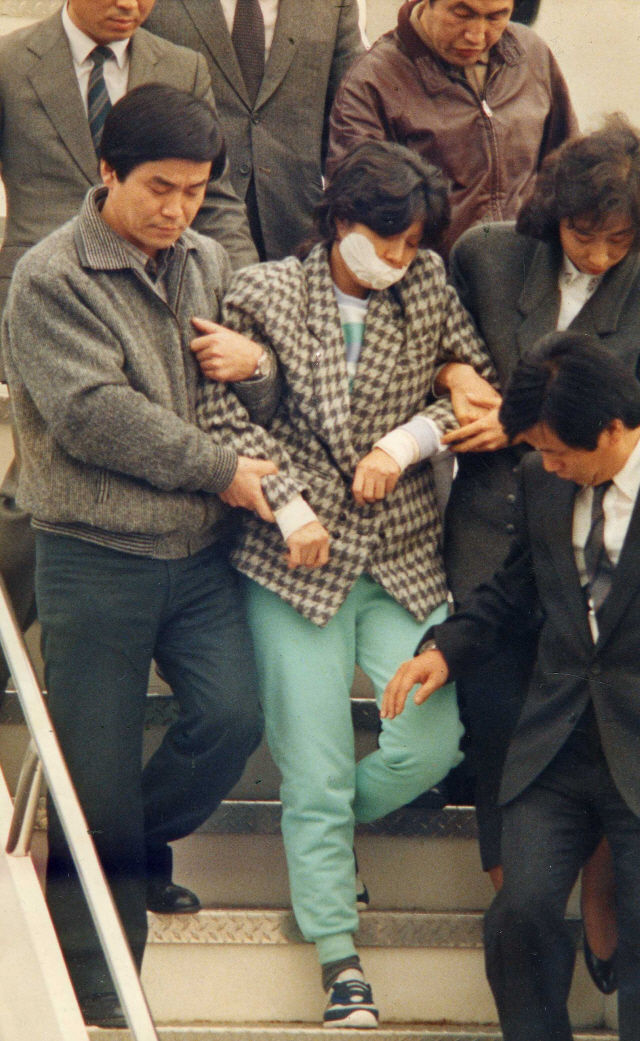 대한항공 858여객기 폭파 혐의를 받고 있는 김현희가 당국에 체포되어 KAL 특별기편으로 1987년 12월 15일 김포공항에 도착, 수사관들과 함께 경찰 앰브런스로 향하고 있다./연합뉴스