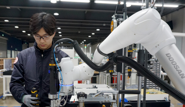 두산로보틱스 수원 공장에서 인간의 팔 모양을 한 협동로봇이 작업자 곁에서 또 다른 로봇 상품의 조립을 돕고 있다. /사진제공=두산로보틱스