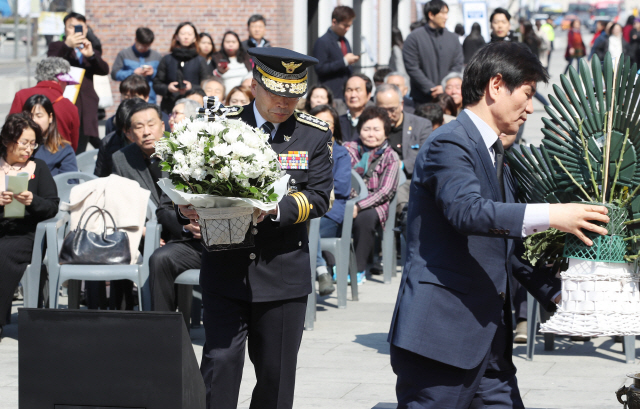 3일 서울 광화문광장에서 열린 ‘제주 4·3사건’ 71주년 추념식에 참석한 민갑룡(앞줄 왼쪽) 경찰청장이 헌화를 위해 흰 국화꽃이 담긴 바구니를 옮기고 있다./연합뉴스