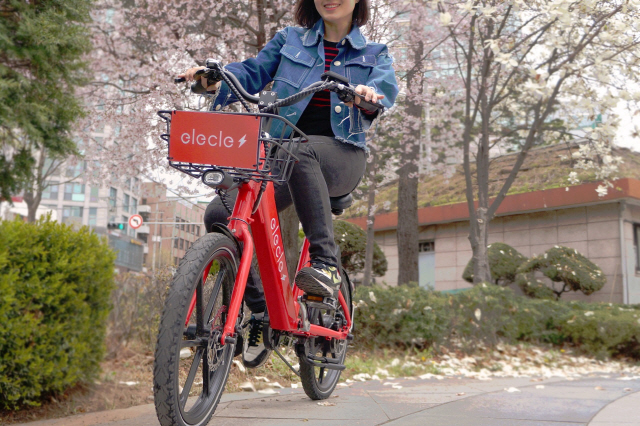 쏘카 모델이 일레클의 전기자전거를 타고 벚꽃길을 달리고 있다./사진제공=쏘카