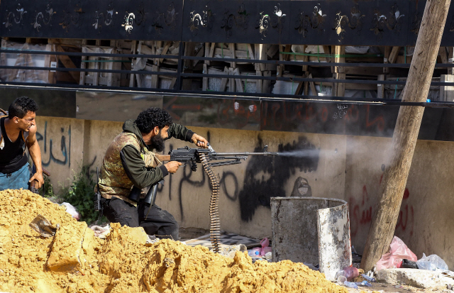 지난 10일(현지시간) 트리폴리 인근 교외지역에서 통합정부군(GNI) 소속 전투원이 리비아국민군(LNA)를 향해 기관총을 쏘고 있다./트리폴리=AFP연합뉴스