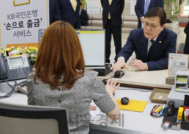 12일 서울 여의도 KB국민은행 본점에서 열린 ‘손으로 출금 서비스’ 출시 기념식에서 최종구(오른쪽) 금융위원장이 손바닥 정맥 인증만으로 예금 출금이 가능한 ‘손으로 출금 서비스’를 시연하고 있다.     /사진제공=KB국민은행