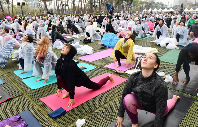 14일 서울 롯데백화점 잠실점 월드파크에서 열린 '요가말라 프로젝트'에서 참가자들이 봄비를 맞으며 요가를 하고 있다. 롯데백화점은 창립 40주년을 기념해 이날 '요가쿨라'와 함께 글로벌 요가 축제를 진행했다./권욱기자 2019. 04. 14