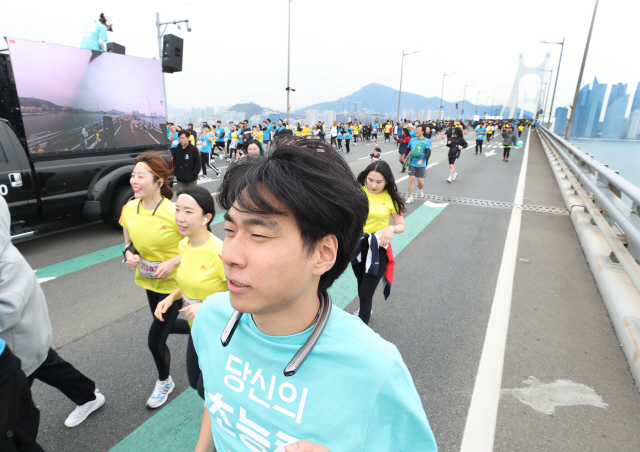 KT 직원이 14일 부산 광안리 일대에서 열린 ‘2019 마이런 부산’에서 넥밴드형 카메라로 찍은 360도 영상이 모니터 차량에 실시간 중계되고 있다. 이번 대회에서 KT는 이같은 ‘리얼360’ 라이브 중계 등 차별화한 5세대(5G) 기술을 선보였다. /사진제공=KT