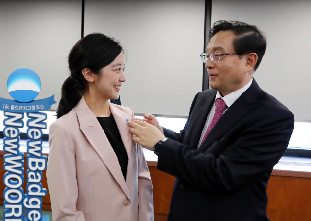 손태승(오른쪽) 우리금융그룹 회장이 15일 서울 중구 우리은행 본점 투게더룸에서 열린 그룹경영협의회에서 한 직원에게 ‘여명’을 모티브로 새롭게 디자인한 배지를 달아주고 있다. /사진제공=우리금융지주