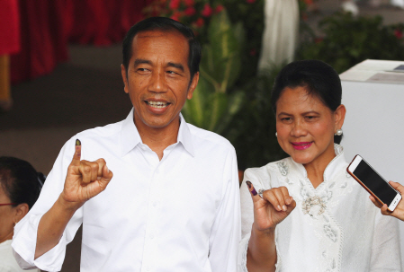 조코 위도도 인도네시아 대통령이 17일(현지시간) 부인과 투표한 후 잉크가 묻은 새끼손가락을 들어 보이고 있다. /자카르타=로이터연합뉴스
