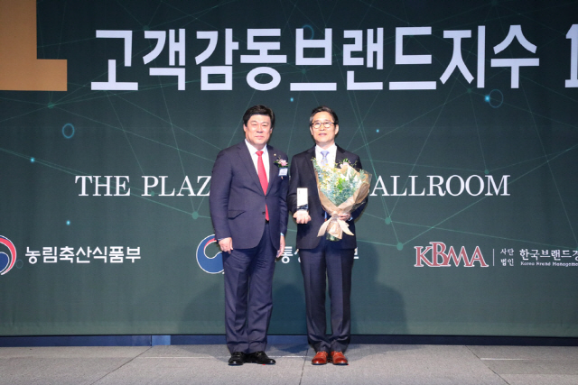 이의환(오른쪽) 에이원 대표가 18일 서울 더플라자호텔에서 열린 ‘2019 고객감동브랜드지수 인증식’에서 화환을 들고 미소를 보이고 있다./사진제공=에이원