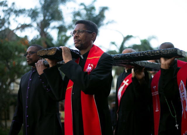 19일(현지시간) 남아프리카공화국 더반에서 교회 지도자들이 성금요일 행사에 참가해 십자가를 운반하고 있다. /더반=로이터연합뉴스