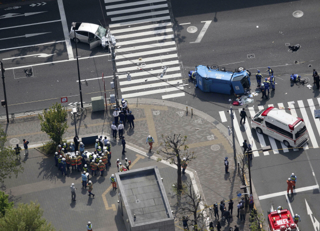 19일(현지시간) 일본 도쿄 이케부쿠로에서 경찰이 교통사고 현장을 조사하고 있다. 이날 낮 87세 남성이 몰던 승용차(왼쪽 위 흰색)가 신호등이 빨간 불인데도 질주해 횡단보도를 건너는 행인들을 들이받은 뒤 쓰레기차(파란색)와 충돌했다. /도쿄=교도연합뉴스