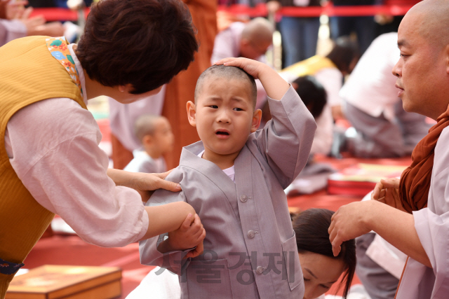 22일 서울 종로구 조계사 대웅전 앞 마당에서 열린 보리수 새싹학교 동자승 단기출가 삭발수계식에서 한 동자승이 삭발을 마친 후 어색한 듯 머리를 만지고 있다./권욱기자 2019.04.22