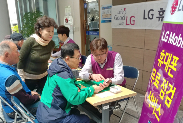 LG전자 직원들이 지난 11일 경남 창원시 소재 마산노인종합복지관에서 고객들에게 찾아가는 휴대폰서비스를 제공하고 있다./사진제공=LG전자