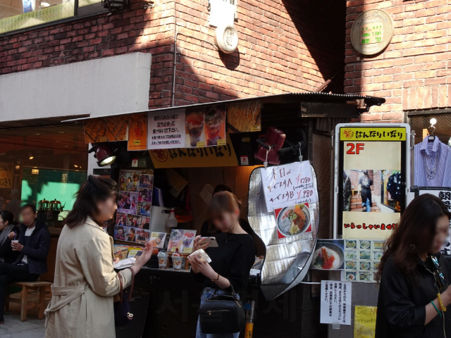 관광객들이 가마쿠라의 대표적인 길거리 음식 명소 코마치 거리에서 음식을 받아들고 사진을 찍고 있다./송주희기자