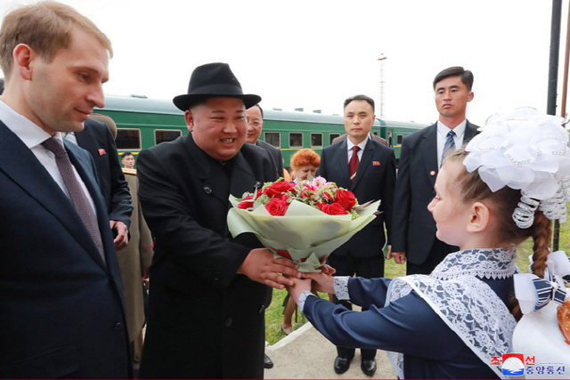 조선중앙통신이 김정은 국무위원장의 러시아 입성 소식을 하루 만인 25일 보도했다. 사진은 중앙통신이 공개한 사진으로, 중간 기착지인 하산역에 내린 김 위원장이 전통 의상을 입은 러시아 어린이에게 꽃다발을 건네받고 있다. /연합뉴스