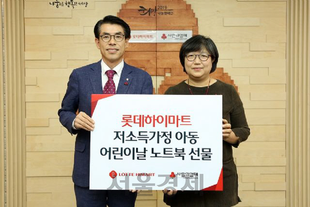 박수용(왼쪽) 롯데하이마트 모바일부문장이 김연순 사랑의열매 사회복지공동모금회 사무총장과 노트북 전달식 기념 촬영을 하고 있다./사진제공=롯데하이마트