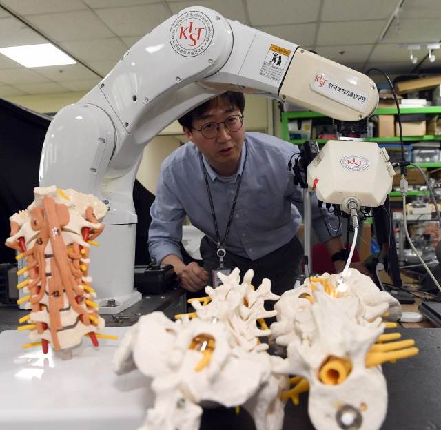 이득희 KIST 의료로봇연구단장이 정밀시술로봇 ‘닥터허준’으로 척추 모형에 시술도구를 삽입하는 동작을 시연하고 있다.   /이호재기자