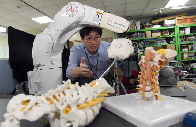 이득희 KIST 의료로봇연구단장이 중재시술로봇 ‘닥터허준’으로 척추 모형에 시술도구를 삽입하는 동작을 시연하고 있다.   /이호재기자