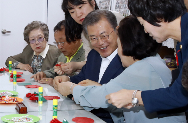 문재인 대통령과 부인 김정숙 여사가 7일 오전 금천구 치매안심센터를 방문, 치매 어르신들과 함께 종이접기로 카네이션을 만들고 있다./연합뉴스