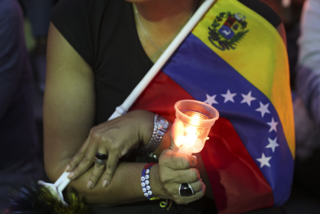 니콜라스 마두로 정부에 반대하는 한 베네수엘라 시민이 5일(현지시간) 카라카스에서 국기와 촛불을 들고 있다. /카라카스=AP연합뉴스