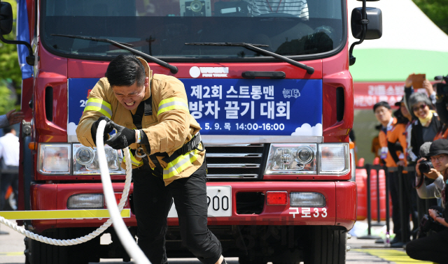 9일 오후 서울 영등포구 여의도공원에서 열린 '제2회 스트롱맨 소방차 끌기 대회'에 참가한 소방관이 맨몸으로 11t의 소방차를 끌고 있다./오승현기자 2019.5.9