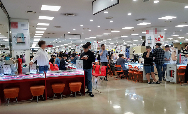 서울 신도림 테크노마트 집단상가를 방문한 소비자들이 스마트폰을 살펴보고 있다./권경원기자