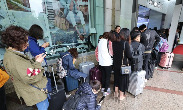 서울의 한 면세점 앞에서 외국인들이 들어가기를 기다리고 있는 모습이다./연합뉴스