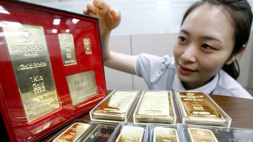 신한은행 직원이 원·달러 환율로 환산한 국내 금 시세로 실물 금에 투자할 수 있는 골드바 상품을 소개하고 있다. /사진제공=신한은행