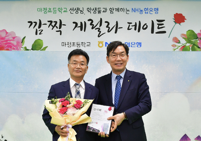 15일 경기 파주시 마정초등학교에서 진행된 ‘고객과 함께하는 깜짝 게릴라 데이트’ 행사에서 이대훈(오른쪽) NH농협은행장이 곽규종 마정초등학교장과 기념사진을 촬영하고 있다. 이날 이 행장은 학교 측에 공기청정기를 기증했으며 선생들에게는 감사패와 꽃다발·카네이션을, 학생들에게는 학용품과 미세먼지 마스크를 전달했다./사진제공=농협은행