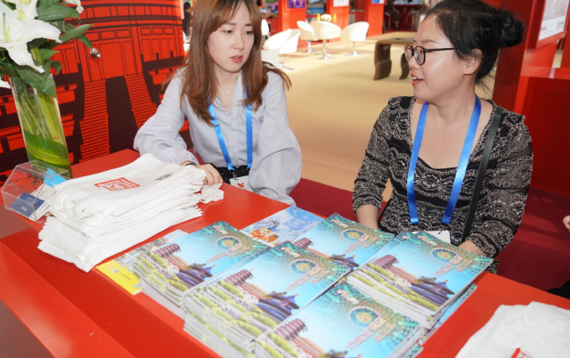 16일 중국 베이징의 ‘농업전람관’에서 열린 ‘아시아 문화관광전’에서 베이징시문화관광국 관계자들이 한국어 ‘베이징 여행 가이드’를 나눠주고 있다.