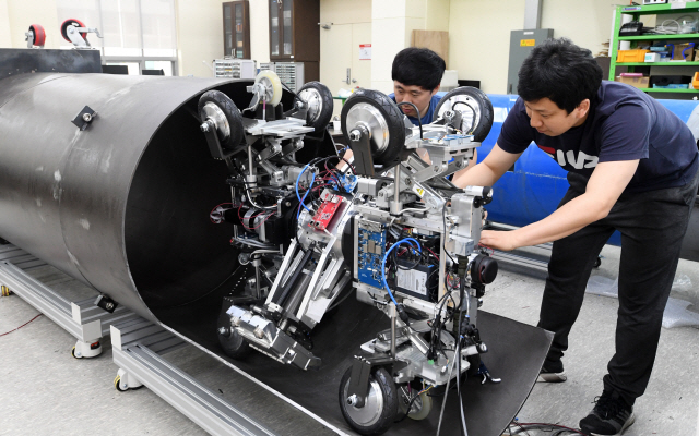 한국로봇융합연구원 연구진이 배관검사용 로봇을 산업용 파이프라인에 투입하고 있다. /포항=권욱기자