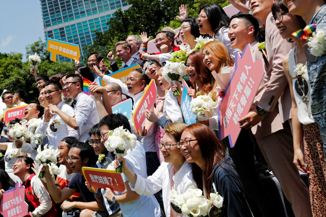 아시아 최초로 동성 간 결혼을 법제화한 대만에서 결혼 등기 업무가 정식 시작된 24일(현지시간) 수도 타이베이에서 관공서 등기를 마친 동성 커플들이 단체 기념사진을 찍기 위해 포즈를 취하고 있다. /타이베이=로이터연합뉴스