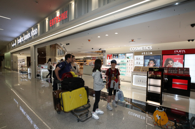 해외여행객들이 29일 개장을 앞둔 인천국제공항 입국장 면세점을 구경하며 지나가고 있다. 1·2터미널에 신설되는 면세점은 오는 31일 영업을 시작하며 면세한도는 600달러다./연합뉴스