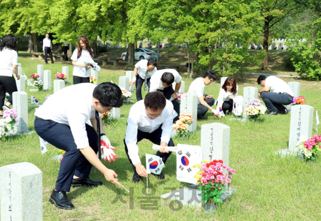 김규식(사진 앞줄 왼쪽에서 두번째) 맥키스컴퍼니 대표이사 등 이제우린봉사단이 묘역 태극기 꽂기 봉사활동을 펼치고 있다. 사진제공=맥키스컴퍼니