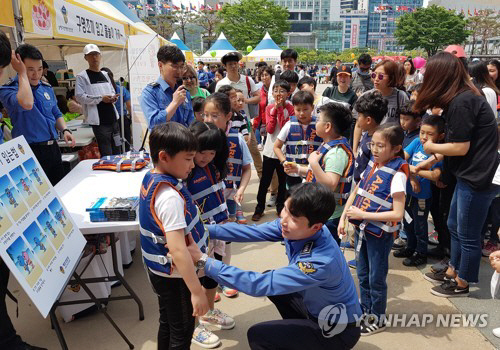 지난달 5일 부산 벡스코 야외광장에서 남해해경청 경찰관으로부터 구명조끼 착용법을 배운 어린이들이 구명조끼를 입어보고 있다./연합뉴스