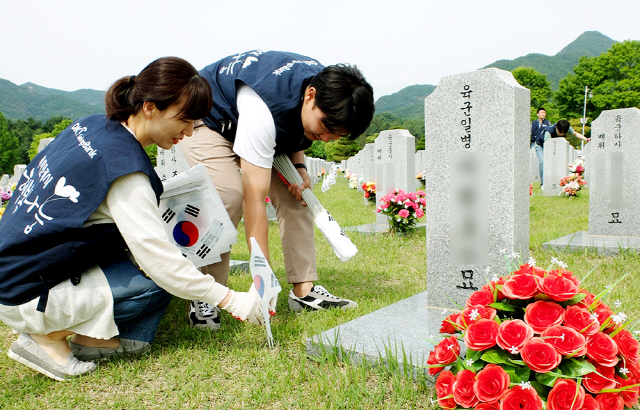 지난 1일 대전 국립대전현충원에서 OK저축은행 직원들이 묘비를 닦고 태극기를 꽂으며 순국선열을 기리고 있다./사진제공=OK저축은행