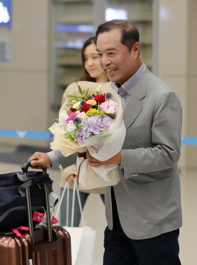 자유한국당 김병준 전 비상대책위원장이 미국 방문을 마치고 4일 인천국제공항을 통해 귀국하며 꽃다발을 받고 환하게 웃고 있다. /연합뉴스