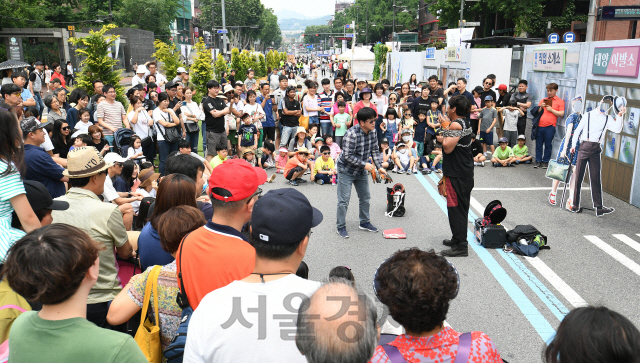 '2019 대학로 차 없는 거리'의 시범운영이 시작된 9일 서울 종로구 대학로에서 시민들이 익살스러운 마술 공연을 관람하고 있다. 지난 1989년부터 운영이 중단됐던 '대학로 차 없는 거리'는 '낭만과 추억을 회상하는 어게인(Again)1989!'를 슬로건으로 30년 만에 부활했다./오승현기자 2019.6.9