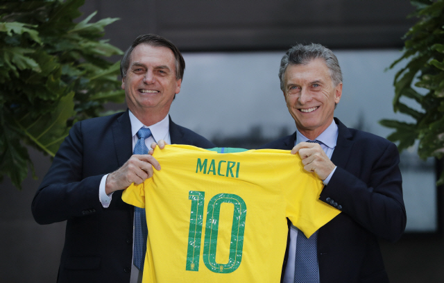 아르헨티나를 방문한 자이르 보우소나루(왼쪽) 브라질 대통령이 지난 6일(현지시간) 부에노스아이레스에서 마우리시오 마크리 아르헨티나 대통령에게 그의 이름이 쓰인 축구 유니폼을 전달하며 환하게 웃고 있다. /부에노스아이레스=AP연합뉴스