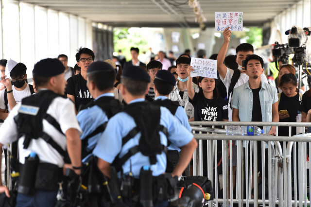 14일 홍콩에서 ‘범죄인 인도 법안’ 반대집회를 열고 있는 시위대가 경찰의 강경진압을 규탄한다는 내용의 피켓을 들고 경찰과 대치하고 있다.        /홍콩=AFP연합뉴스