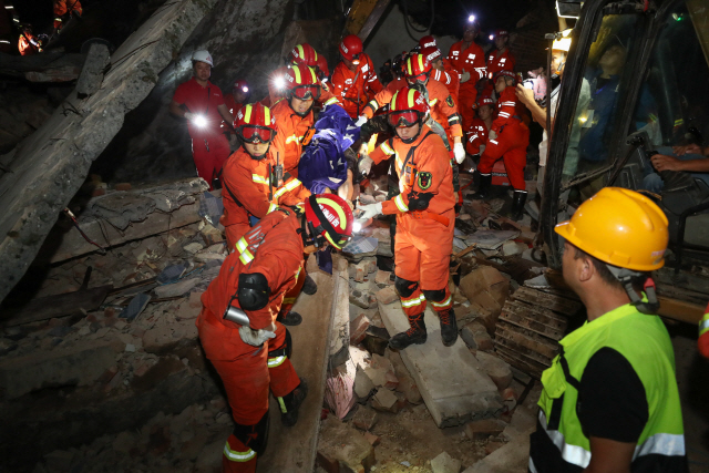 18일 중국 서남부 쓰촨성 이빈시에서 전날 발생한 규모 6.0의 강진으로 무너진 건물에 출동한 구조대가 부상자를 옮기고 있다. 이번 지진으로 13명이 숨지고 200명이 다친 것으로 집계됐다. /쓰촨성=신화연합뉴스