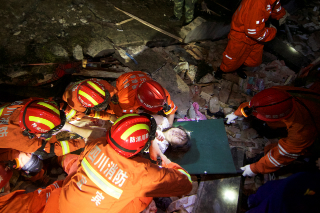 중국 구조대원들이 18일(현지시간) 쓰촨성 이빈시 창닝현에서 지진으로 무너져내린 건물 잔해에 깔린 여성을 구조하고 있다. /이빈=로이터연합뉴스