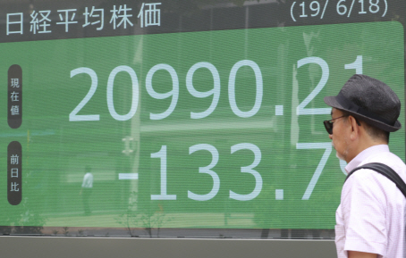지난 18일 한 행인이 도쿄의 한 증권사 주가전광판 앞을 지나가고 있다.     /AP연합뉴스