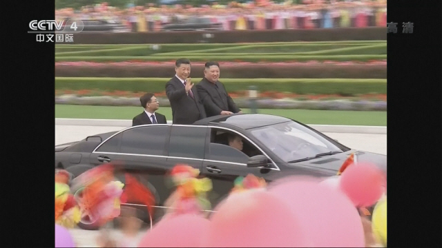 시진핑 중국 국가주석과 김정은 북한 국무위원장이 20일 평양거리에서 카퍼레이드를 하며 거리에 늘어선 환영 인파를 향해 손을 흔들고 있다./CCTV 캡처
